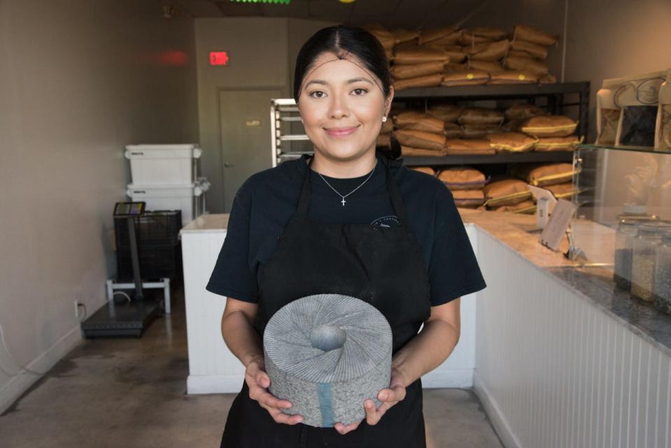 Claudia Monroy displays a corn-grinding stone at her Sierra Madre tortilla factory and shop, which offers authentic, organic Mexican tortillas in Lake Worth Beach.