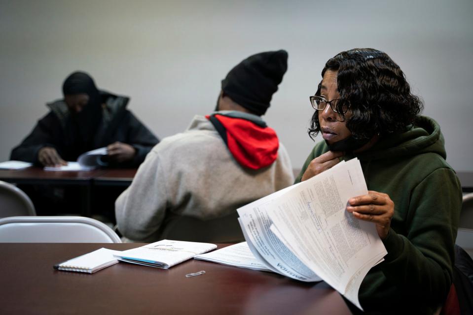 Rocale Worthy, 53, right, who hopes to secure stable housing, looks through paperwork at the start of a housing voucher meeting at RPI Management, Inc. in Dearborn on Jan. 20, 2023.