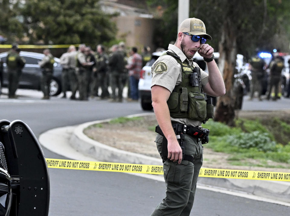 A Riverside County Sheriff's deputy wipes his eye as he stands near the corner of Golden West Ave. and Condor Drive in Jurupa Valley, Calif. Thursday, Dec. 29, 2022. Authorities say a Southern California sheriff’s deputy has been shot during a traffic stop. (Will Lester/The Orange County Register via AP)