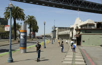 In this photo taken Thursday, April 18, 2019, a man rides a scooter and children play along the Embarcadero across the street from the proposed site of a homeless shelter in San Francisco. The city of San Francisco, which has too little housing and too many homeless people sleeping in the streets, is teeming with anxiety and vitriol these days. A large new homeless shelter is on track to go up along a scenic waterfront area dotted with high-rise luxury condos, prompting outrage from some residents. (AP Photo/Eric Risberg)