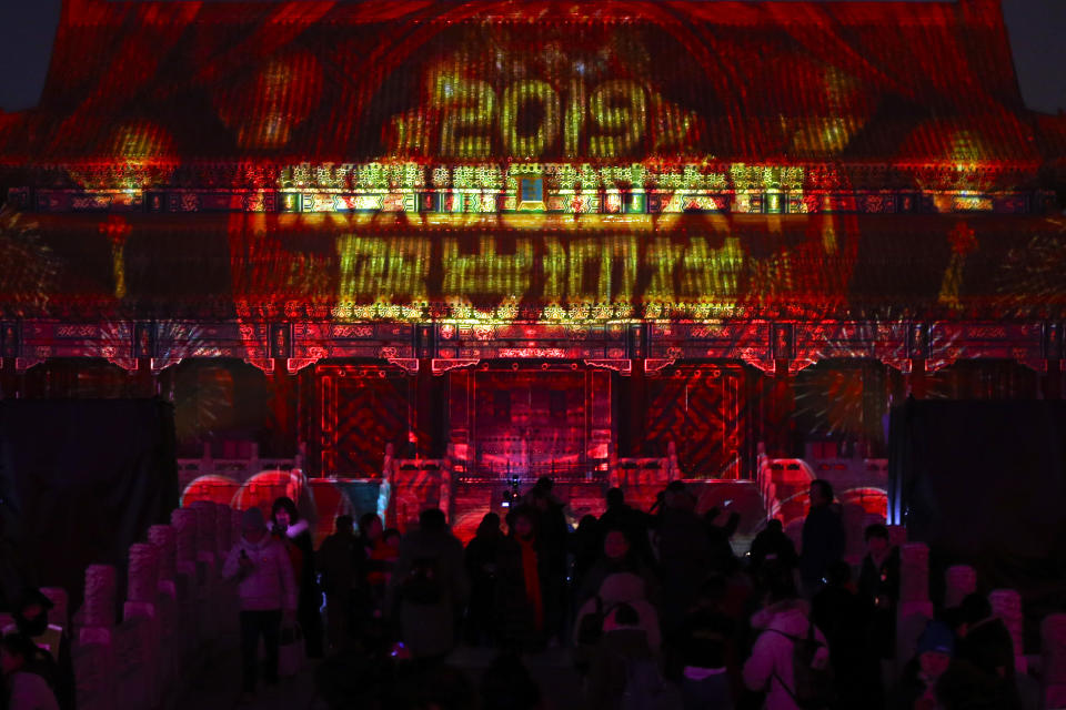 In this Tuesday, Feb. 19, 2019, photo, visitors tour the Forbidden City projected with colorful lights and prosperous words for the Lantern Festival in Beijing. China lit up the Forbidden City on Tuesday night, marking the end of 15 days of lunar new year celebrations. It was not a Lantern Festival the last emperor, who abdicated in 1912, would have recognized. There were lanterns, but those lucky enough to snag tickets saw a laser light show and historic buildings bathed in colorful lights. Others watched from outside the vast walled compound in Beijing, from where Ming and Qing dynasty emperors ruled for five centuries. (AP Photo/Andy Wong)