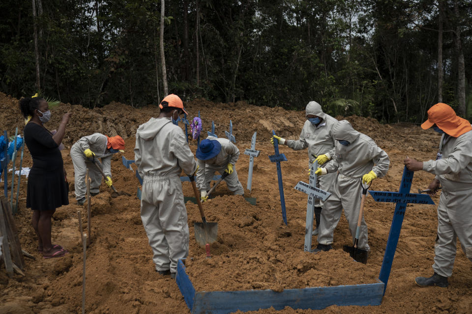 Cemetery workers place crosses over a common grave after burying five people at the Nossa Senhora Aparecida cemetery amid the new coronavirus pandemic in Manaus, Brazil, Wednesday, May 13, 2020. The new section of the cemetery was opened last month to cope with a surge in deaths. (AP Photo/Felipe Dana)