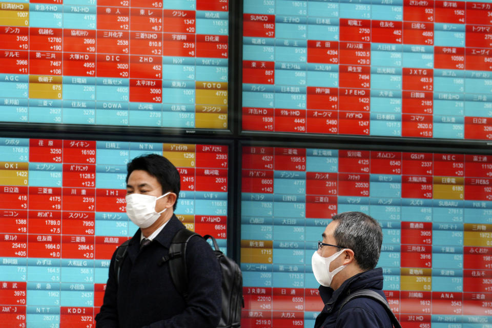 People walk in front of an electronic stock board showing Japan's Nikkei 225 index at a securities firm in Tokyo Friday, Jan. 24, 2020. Shares are mostly higher in quiet trading as China closes down for its week-long Lunar New Year festival. (AP Photo/Eugene Hoshiko)