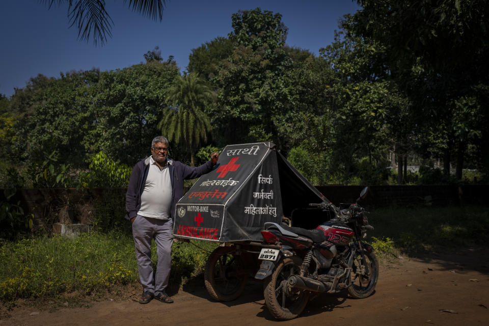 Bhupesh Tiwari from Saathi, non-profit organisation, poses with a first motorbike ambulance, a two-wheeler with a sidecar consisting of a hospital bed on wheels, which he had designed in 2014 with the support of UNICEF, in Kodagoan in central India's Chhattisgarh state, Nov. 15, 2022. These ambulances, first deployed in 2014, reach inaccessible villages to bring pregnant women to an early referral center, a building close to the hospital where expectant mothers can stay under observation, routinely visit doctors if needed until they give birth. Since then the number of babies born in hospitals has doubled to a yearly average of about 162 births each year, from just 76 in 2014. The state has one of the highest rates of pregnancy-related deaths for mothers in India, about 1.5 times the national average, with 137 pregnancy related deaths for mothers per 100,000 births. (AP Photo/Altaf Qadri)