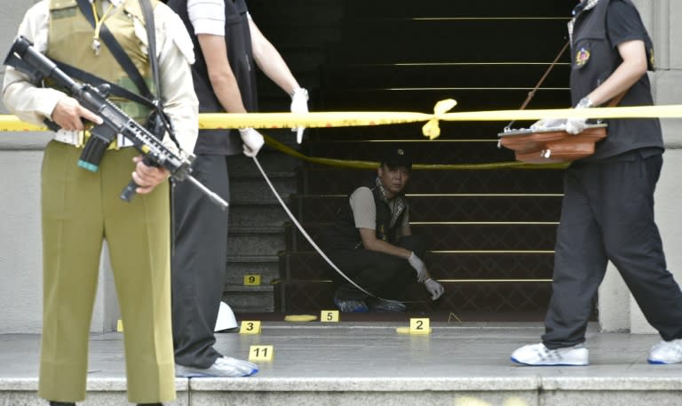 An armed military policeman keeps watch as investigators collect evidence at the scene where a samurai sword-wielding attacker slashed a police guard at the Presidential Palace