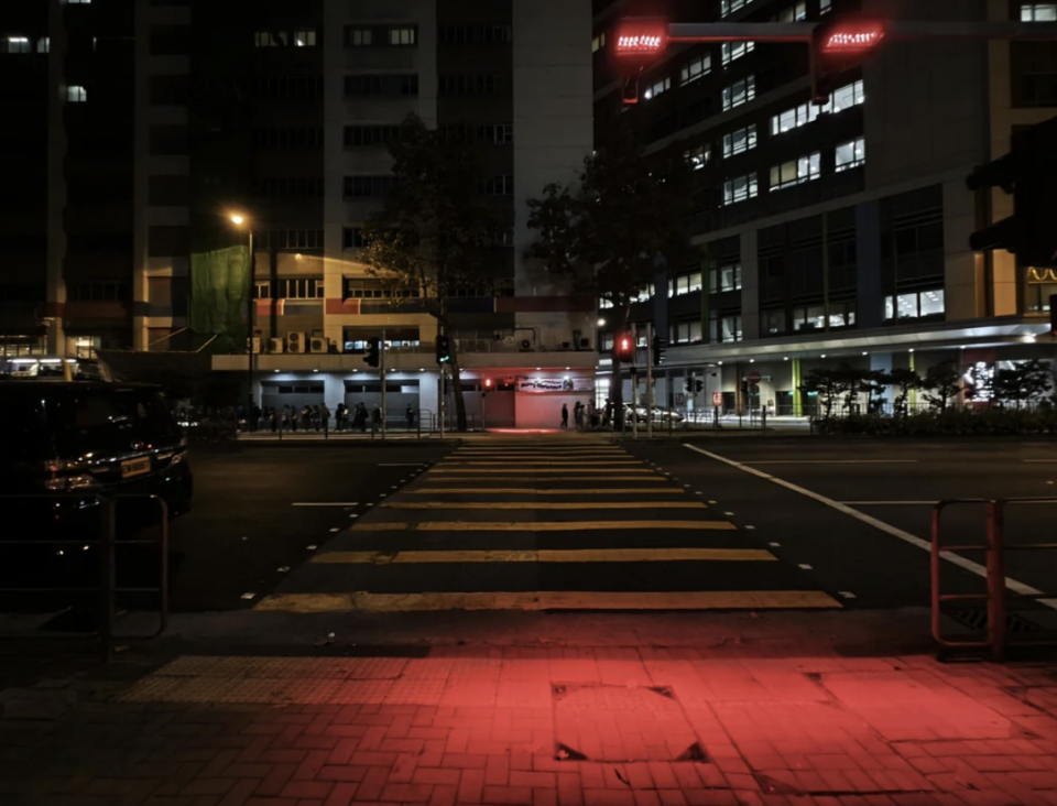 Nighttime city street view with illuminated crosswalk and surrounding buildings