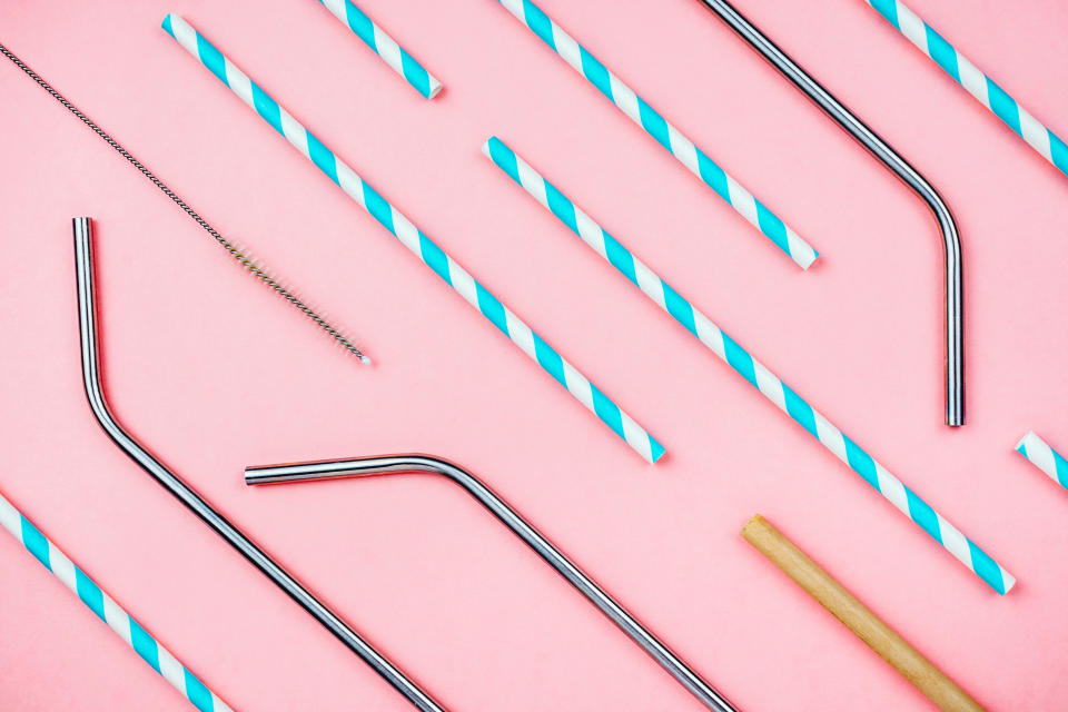 Flatlay of various eco sustainable straws for beverages: paper, metal and bamboo with special brush on pink, concept of zero waste lifestyle