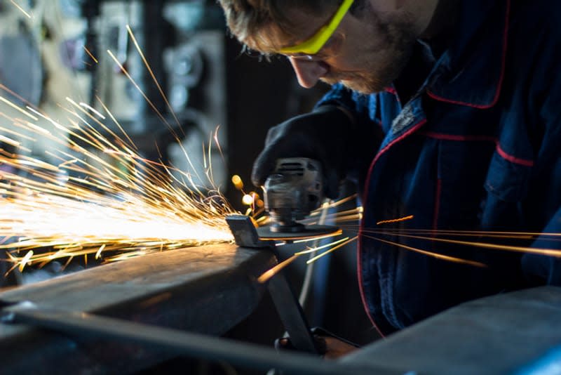 Worker grinding a metal part in his workshop.