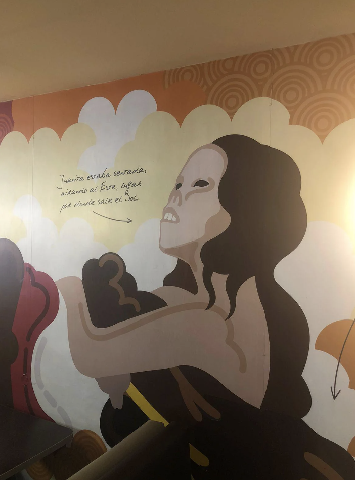 Mural of a stylized woman with open arms and umbrellas, featuring a Spanish quote about searching for the sun