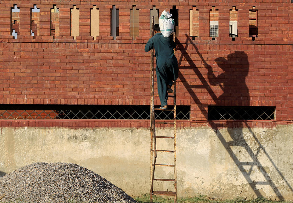 <p>A laborer carries a sack of gravel up a ladder to the roof of a house under construction in Islamabad, Pakistan, May 26, 2017. (Photo: Caren Firouz/Reuters) </p>