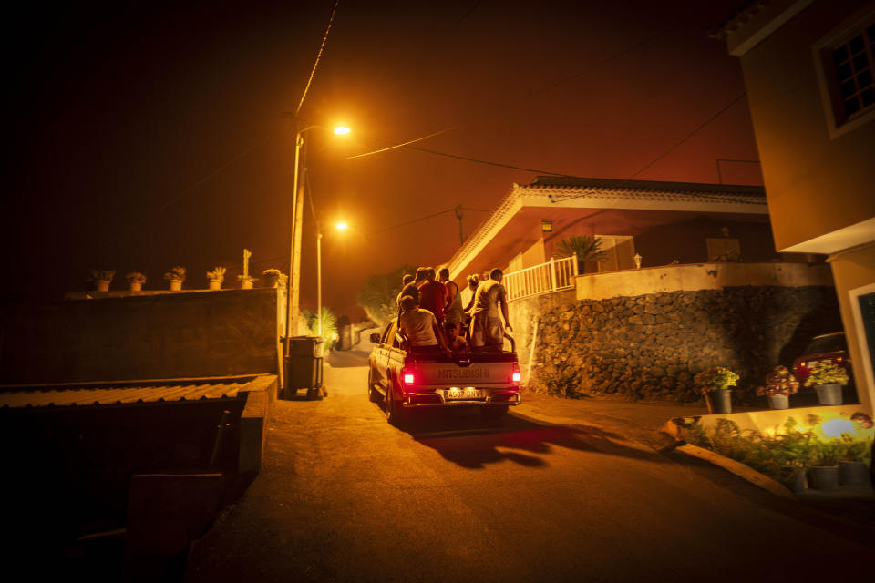 Local residents crowd a van while inspecting their homes as fire advances through the forest in La Orotava in Tenerife, Canary Islands, Spain on Saturday, Aug. 19, 2023. Firefighters have battled through the night to try to bring under control the worst wildfire in decades on the Spanish Canary Island of Tenerife, a major tourist destination. The fire in the north of the island started Tuesday night and has forced the evacuation or confinement of nearly 8,000 people. Regional officials say Friday's efforts will be crucial in containing the fire. (AP Photo/Arturo Rodriguez)