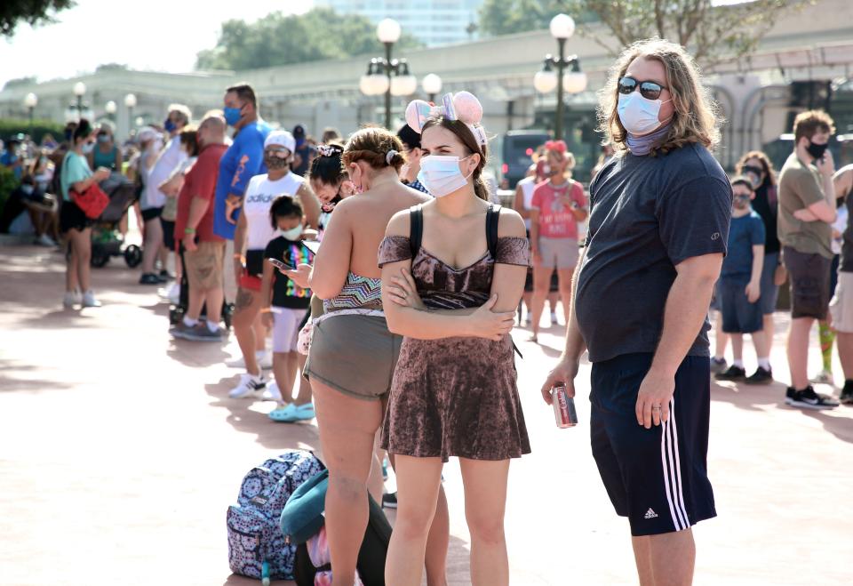 Guests wearing protective masks wait outside the Magic Kingdom theme park at Walt Disney World on the first day of reopening, in Orlando, Florida, on July 11, 2020. - Disney's flagship theme park reopened its doors to the general public on Saturday, along with Animal Kingdom, as part of their phased reopening in the wake of the Covid-19 pandemic. New safety measures have been implemented including mandatory face masks for everyone and temperature checks for guests before they enter. (Photo by Gregg Newton / Gregg Newton / AFP) (Photo by GREGG NEWTON/Gregg Newton/AFP via Getty Images)