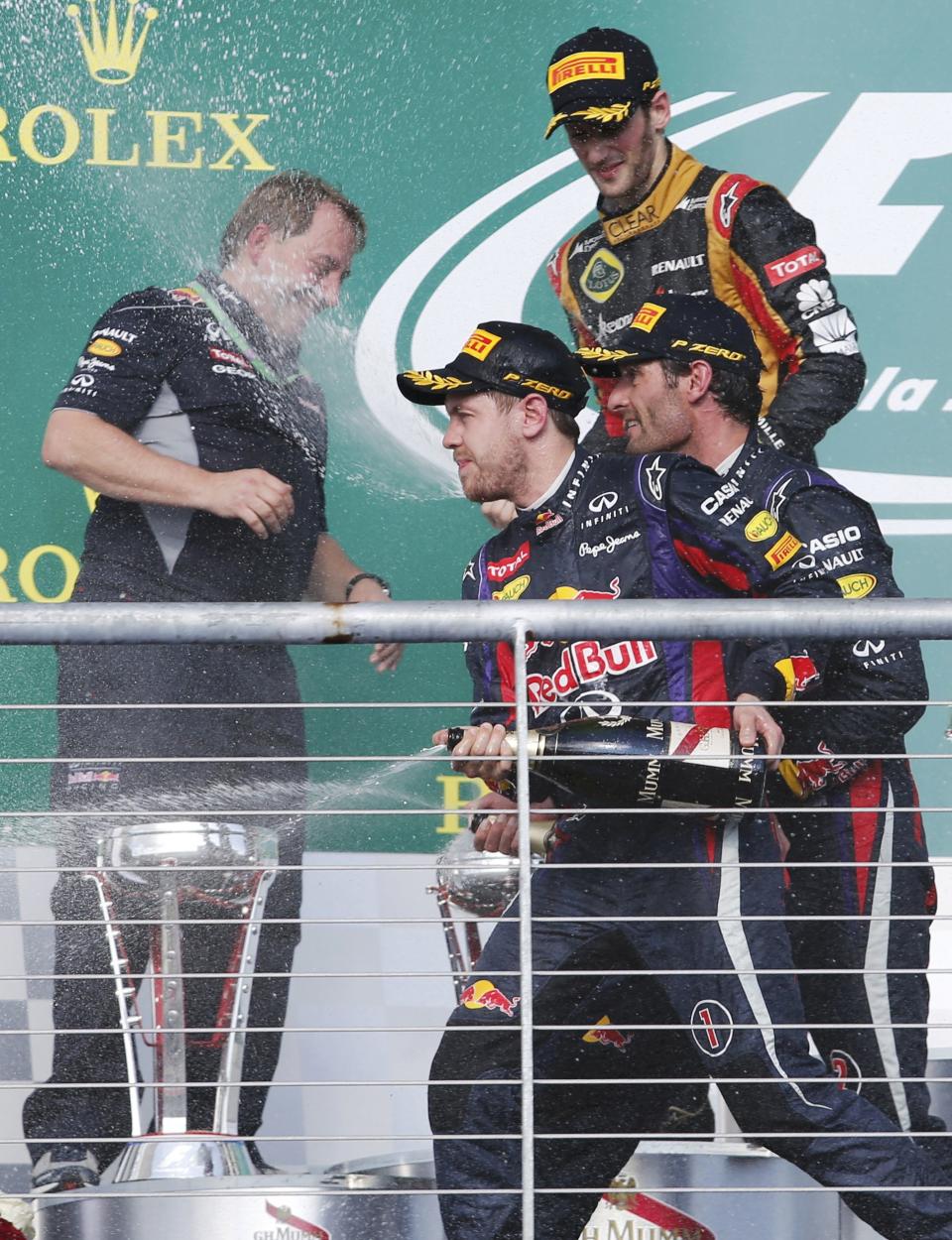 Red Bull Formula One driver Sebastian Vettel (front) of Germany, teammate Mark Webber of Australia (R) and Lotus Formula One driver Romain Grosjean of France (top R) spray champagne next to Red Bull Racing's Head of IT Matt Cadieux during celebrations on the podium after the Austin F1 Grand Prix at the Circuit of the Americas in Austin November 17, 2013.