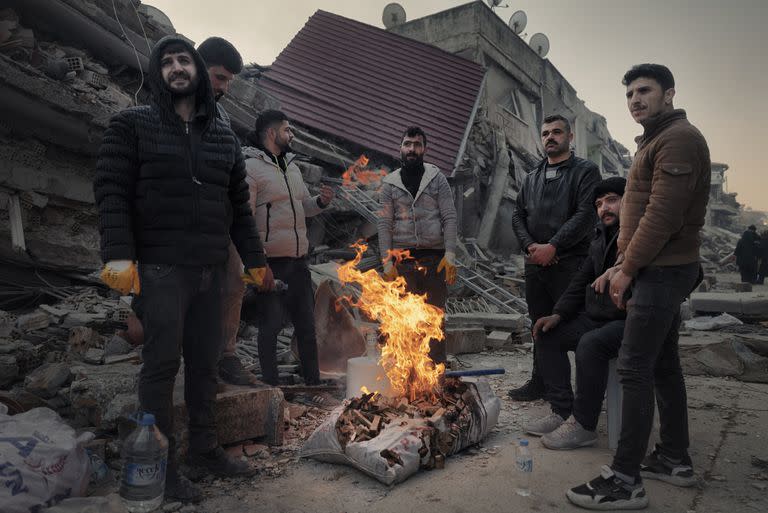Unos hombres se calientan junto a una hoguera en el casco antiguo de Antakya, en la provincia de Hatay, Turquía, tres días después del terremoto, el jueves 9 de febrero de 2023. Los residentes queman todo lo que encuentran para calentarse. (Emily Garthwaite/The New York Times)