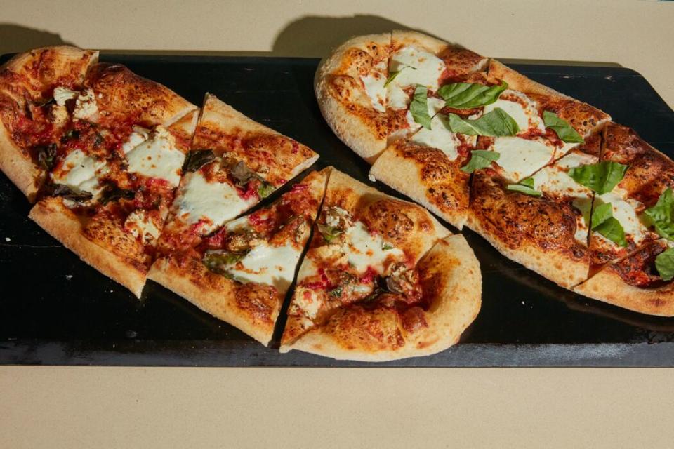 A margherita and garden-inspired flatbread on a cutting board