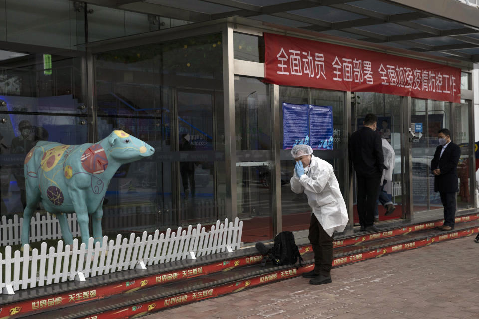 A foreign journalist prepares to wear his mask before entering the office at the Mengniu dairy factory in Beijing on Thursday, Feb. 27, 2020. The state-owned dairy company Mengniu has suffered 20% sales decrease since the beginning of February due to the COVID-19 outbreak, said a Communist Party official overseeing the company during a tour of the plant organized by the State Council Information Office for foreign media. (AP Photo/Ng Han Guan)