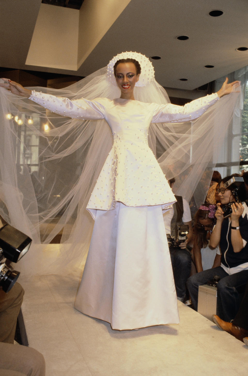 A model is wearing a wedding dress paired with a hat with a long tulle train during the Givenchy fall/winter 1979-1980 couture show in Paris.