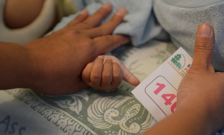 A picture taken on February 10, 2013 shows a mother holding her daughter's hand as she is circumcised in Bandung, Indonesia. The Indonesian government has come under fire after the UN General Assembly in November passed its first resolution condemning female genital mutilation (FGM) which more than 140 million women worldwide have been subjected to