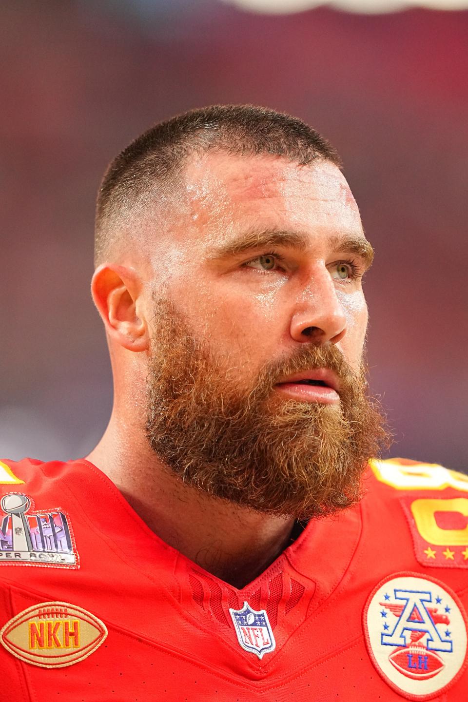 Football player in red jersey, focused expression, with a beard and close-cropped hair