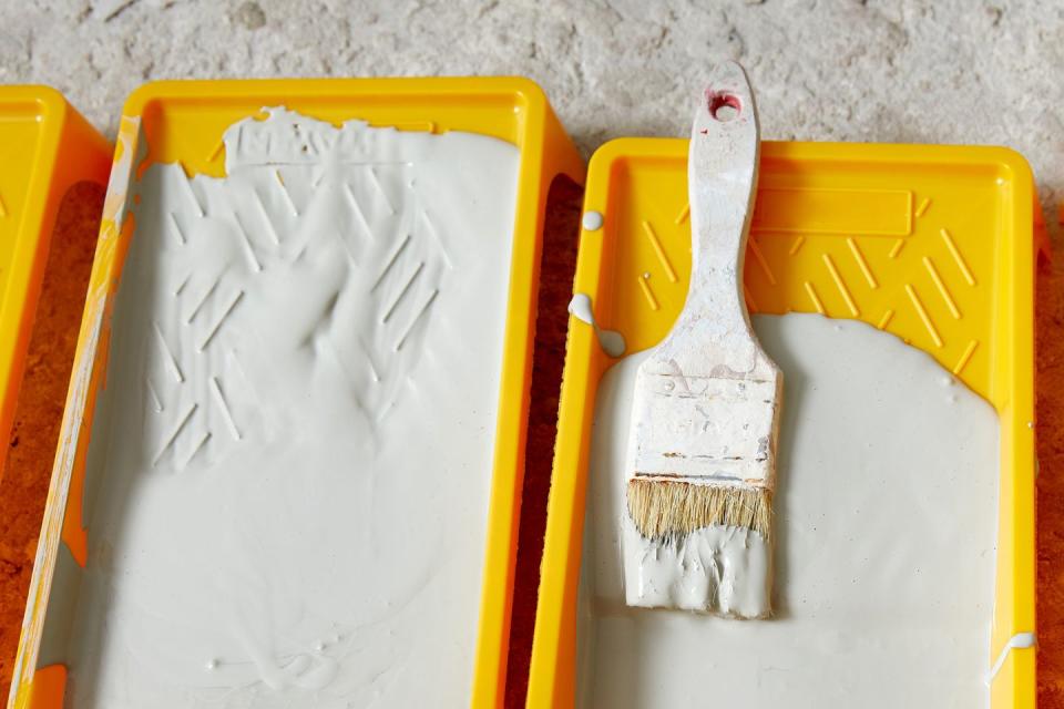 paint tray filled with gray paint an brush tools for the painter and