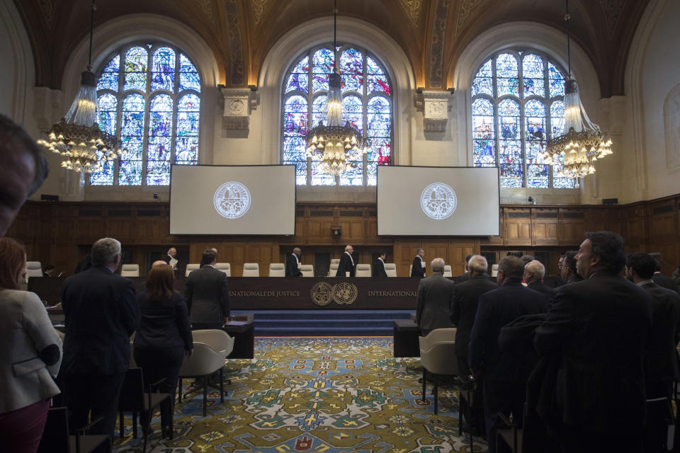 The delegations of the U.S., front left, and the Islamic Republic of Iran, front right, rise as judges, rear, enter the International Court of Justice, or World Court, in The Hague, Netherlands, Wednesday, Oct. 3, 2018, to rule on an Iranian request to order Washington to suspend sanctions against Tehran. (AP Photo/Peter Dejong)