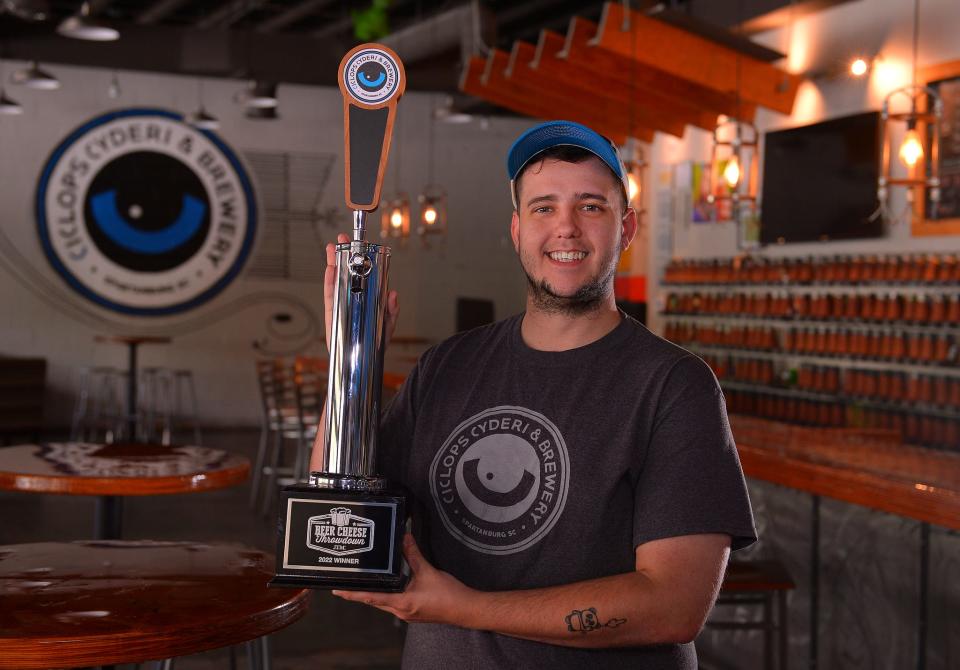 Holden McGinnis, Pub Manager at Ciclops Cyderi & Brewery, holds a trophy at the pub in Spartanburg, Friday, June 3, 2022. They won first place for their beer cheese and Madman Pizza at the National Restaurant Convention competition.