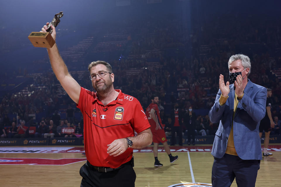 PERTH, AUSTRALIA - JUNE 18: Trevor Gleeson, coach of the Wildcats acknowledges the supporters after being presented the 2021 NBL Coach Of The Year trophy by former Wildcats head coach Alan Black during game one of the NBL Grand Final Series between the Perth Wildcats and Melbourne United at RAC Arena, on June 18, 2021, in Perth, Australia. (Photo by Paul Kane/Getty Images)