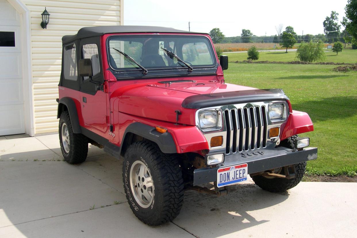 Red 1992 Jeep YJ parked in a driveway on sunny summer day