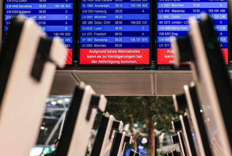 A notice board reads "Due to a warning strike, there may be delays in check-in" at one of 11 major German airports that have started a one-day strike. Oliver Berg/dpa
