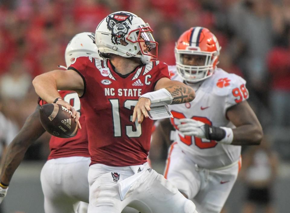 NC State quarterback Devin Leary (13) passes near Clemson defensive end Myles Murphy (98) during the fourth quarter at Carter-Finley Stadium in Raleigh, N.C., September 25, 2021.  The Tigers lost 27-21 in two overtimes game at Carter-Finley Stadium in Raleigh, N.C., September 25, 2021. Leary  was 32-44 for 238  yards and four touchdown passes.