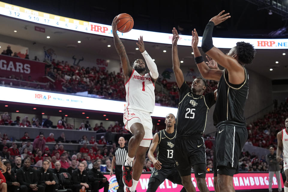 Houston's Jamal Shead (1) goes up for a shot as Central Florida's Taylor Hendricks (25) and Michael Durr, right, defend during the second half of an NCAA college basketball game Saturday, Dec. 31, 2022, in Houston. Houston won 71-65. (AP Photo/David J. Phillip)