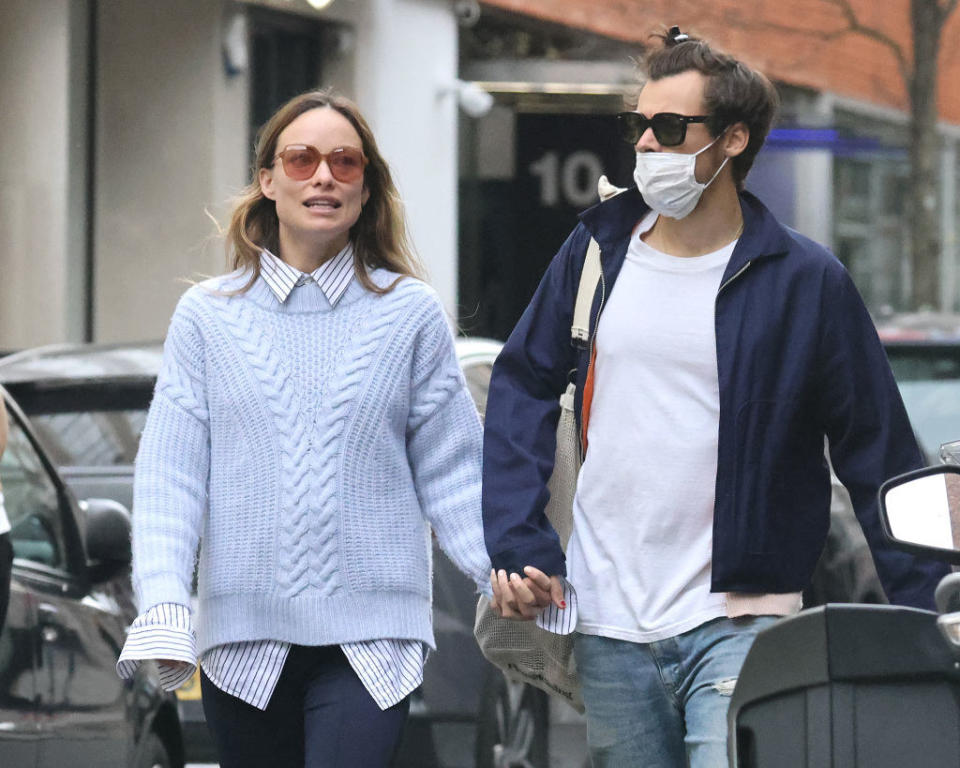 the couple holds hands while walking down the street