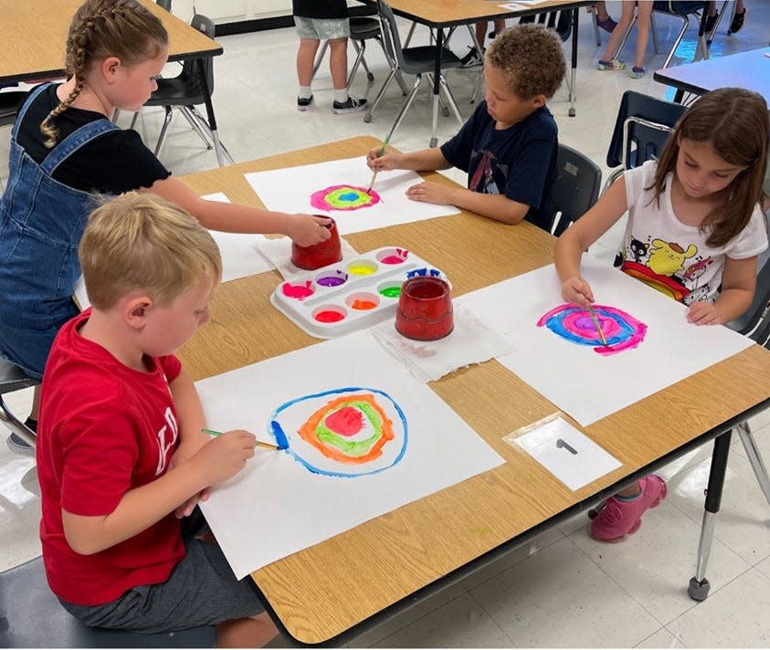 A group of second grade students begin a painting project during art class.