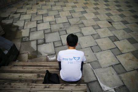 Jiang Hui, whose mother was onboard the missing Malaysia Airlines flight MH370 check the news on his mobile phone before talking to reporters near his home in Beijing, July 30, 2015. REUTERS/Damir Sagolj