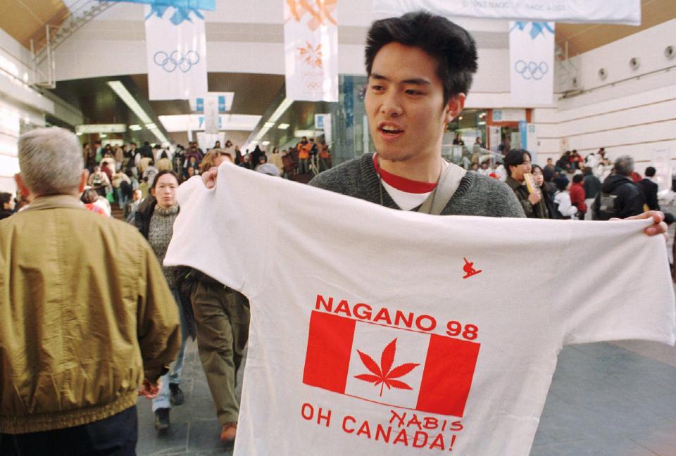 A vendor in the Nagano train station hawks t-shirts showing a Canadian flag with a marijuana leaf substituted for a maple leaf in reference to Canadian snowboarder Ross Rebagliati. (AP Photo/Robert F. Bukatyt)