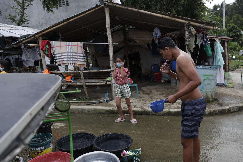 John Paulo Silva, a former resident at Taal volcano, brushes his teeth outside their tent at a relocation site in Balete, Batangas province, Philippines, Sunday, Jan. 10, 2021. Some families are still living in tents and have resorted to taking odd jobs to make a living as the government has prevented them from returning back to their homes almost a year after Taal volcano erupted on Jan. 12, 2020. The eruption displaced thousands of villagers living near the area and delivered an early crisis this year for one of the world's most disaster-prone nations a couple of months before the COVID-19 pandemic broke in the country. (AP Photo/Aaron Favila)