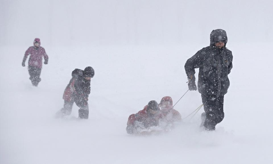 A man runs with a sled carrying children during a snowstorm in Quebec City