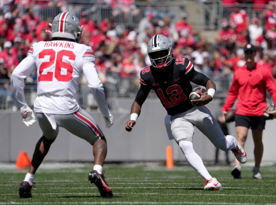 April 13, 2024; Columbus, Ohio, USA; 
Ohio State Buckeyes quarteback ÒAirÓ Noland (12) runs the ball for the scarlet team while defended by safety Cedrick Hawkins Jr. (26) of the grey team during the second half of the LifeSports spring football game at Ohio Stadium on Saturday.