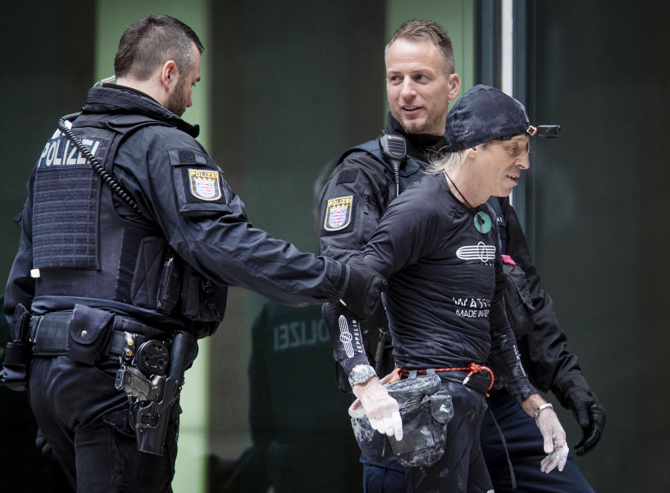 French urban climber Alain Robert, well known as "Spiderman", is escorted by police officers after climbing the 'Skyper' highrise in Frankfurt, Germany, Saturday, Sept. 28, 2019. (AP Photo/Michael Probst)