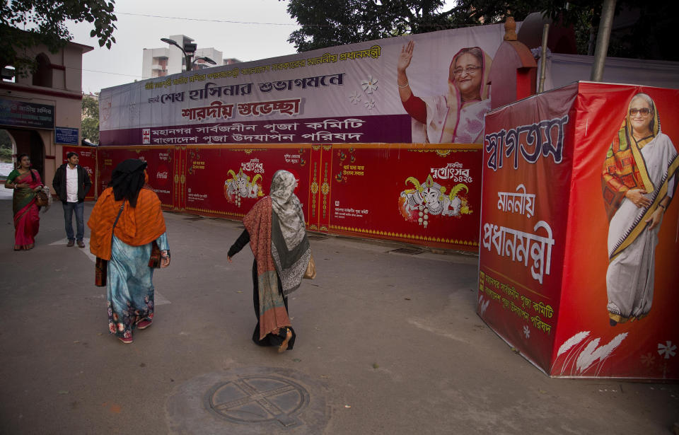 In this Tuesday, Jan. 1, 2019 photo, devotees walk past banners of Bangladeshi Prime Minister Sheikh Hasina near Dhakeshwari Temple in Dhaka, Bangladesh. While Hasina is set to begin her third consecutive term as Bangladesh's prime minister following a landslide election victory, critics say having such an overwhelming majority in parliament could create space for her to become even more authoritarian. Still, Hasina enjoys a lot of support, especially from religious minorities in the Muslim-majority nation who say she has safeguarded their rights. At the Dhakeshwari Temple in Dhaka, Hindus poured in on Tuesday to pray and get a glimpse of the Goddess Durga, something they say was not possible under previous governments. (AP Photo/Anupam Nath)