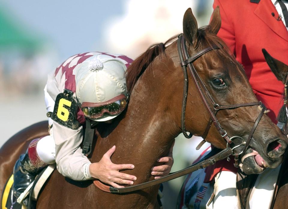 Jockey Jose Santos leans down to kiss Funny Cide after riding the horse to victory in the 2003 Kentucky Derby.