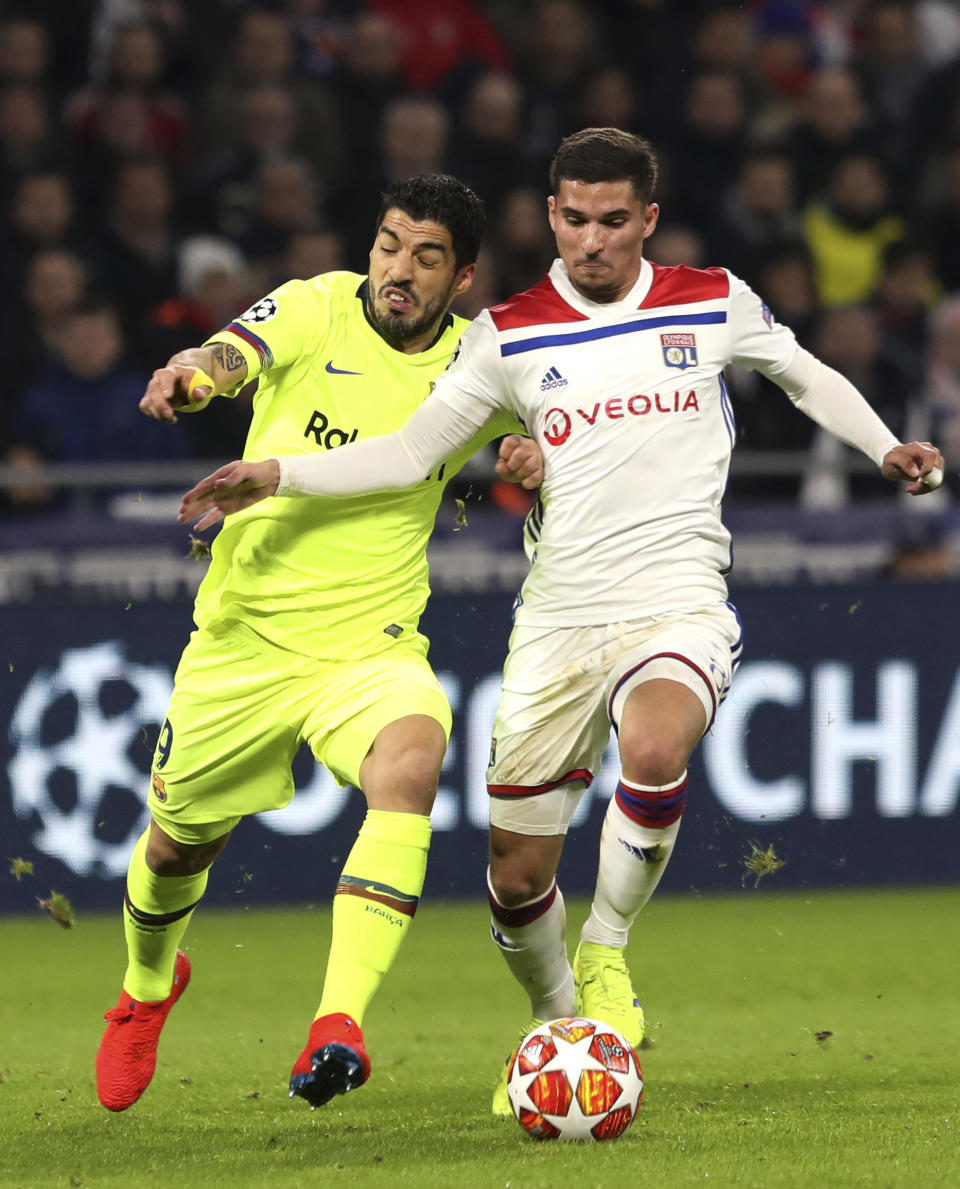 Lyon midfielder Houssem Aouar, right, challenges Barcelona forward Luis Suarez, left, during the Champions League round of 16 first leg soccer match between Lyon and FC Barcelona in Decines, near Lyon, central France, Tuesday, Feb. 19, 2019. (AP Photo/Laurent Cipriani)