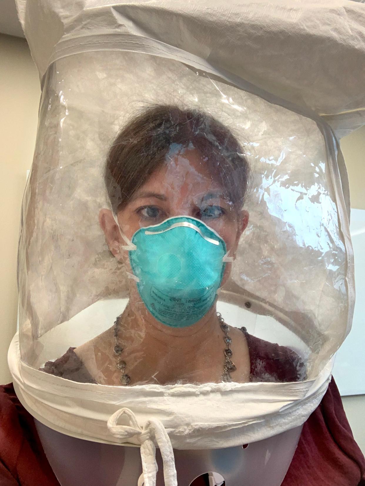 Jennifer Towery dons a special hood while being fitted for an N95 mask. Towery is one of more than 170 office workers from OSF who have volunteered to take on duties in the hospital during the record-breaking COVID-19 surge.