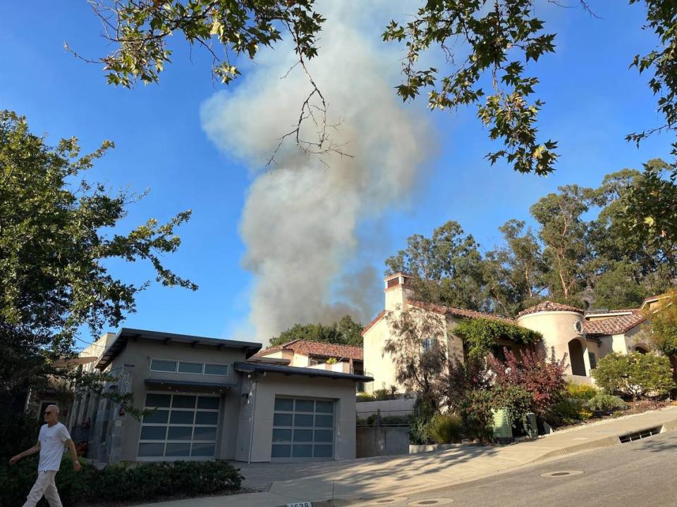 A column of smoke rises from behind homes near San Luis Obispo High School as a vegetation fire burned in the hills on Monday, Oct. 30, 2023.