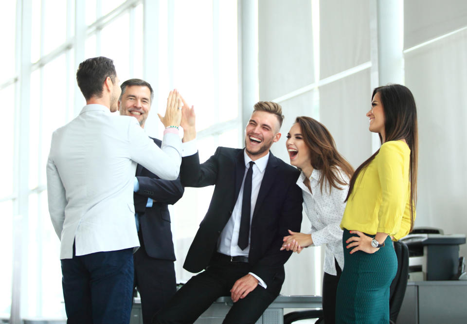 Group of professionally dressed adults smiling and high-fiving