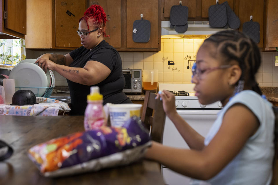 Ke'Arrah Jessie, 9, has a snack while her mom, Ashley Martin, does dishes in Niagara Falls, N.Y., on Monday, April 3, 2023. (AP Photo/Lauren Petracca)