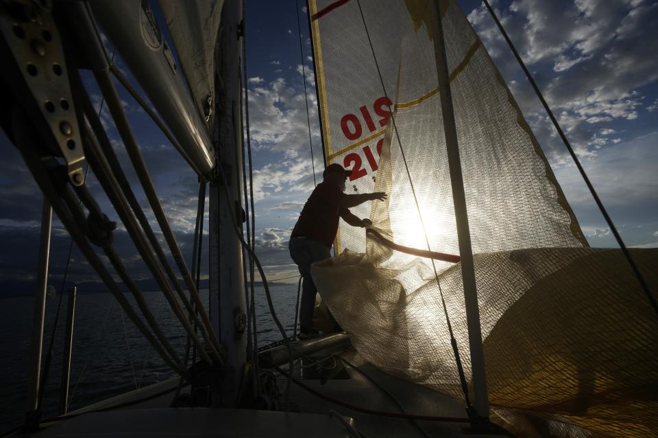Randy Atkin unfurls a sail while boating on the Great Salt Lake on Wednesday, June 14, 2023, near Magna, Utah. Sailors back out on the water are rejoicing after a snowy winter provided temporary reprieve. (AP Photo/Rick Bowmer)