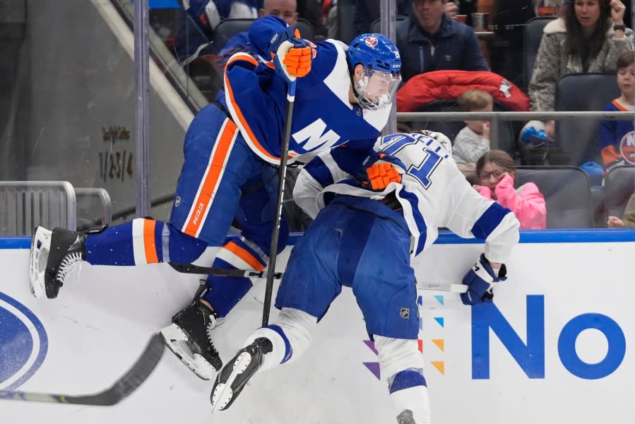 New York Islanders’ Alexander Romanov, left, checks Tampa Bay Lightning’s Anthony Cirelli (71) during the first period of an NHL hockey game Saturday, Feb. 24, 2024, in Elmont, N.Y. (AP Photo/Frank Franklin II)