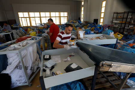 A Palestinian worker arranges items sent by mail eight years ago, after Israel allowed the letters and goods into the West Bank from Jordan, where they were being held, Jericho, in the occupied West Bank August 19, 2018. REUTERS/Mohamad Torokman