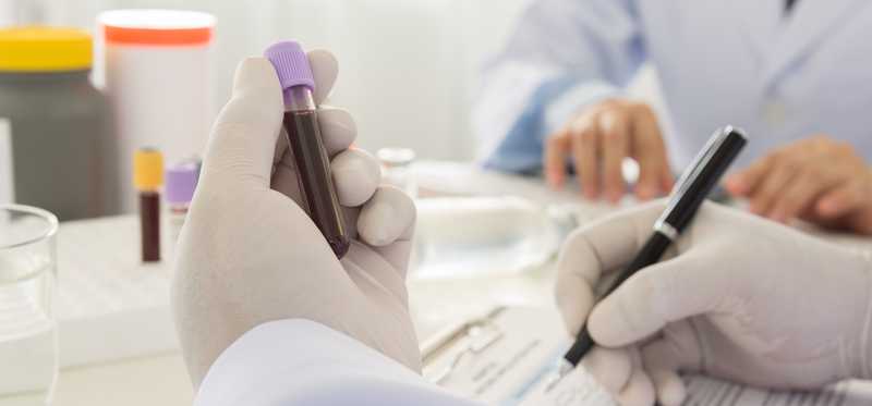 A lab technician notates on a vial of blood.